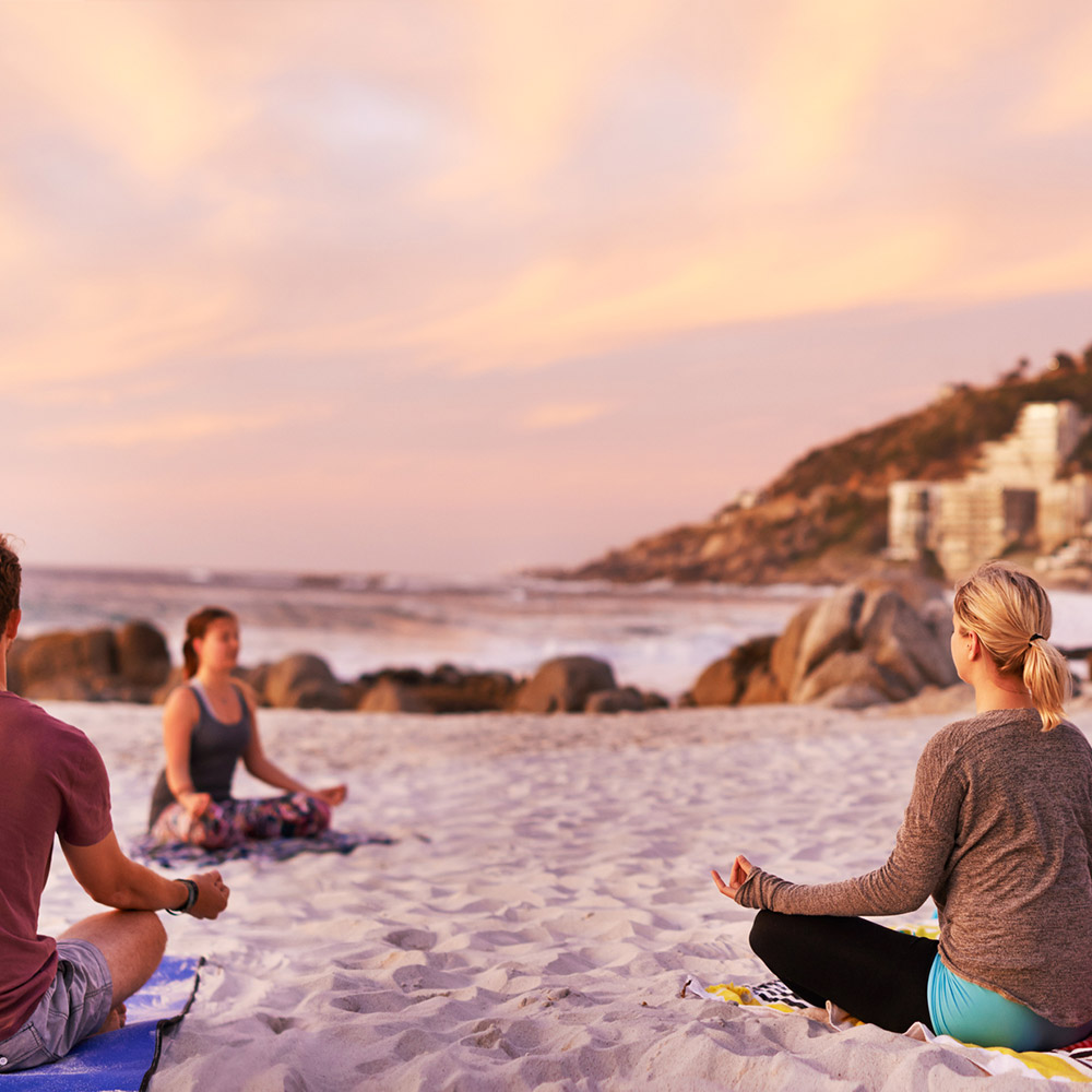 Photo of a group of people having a yoga session on the beach